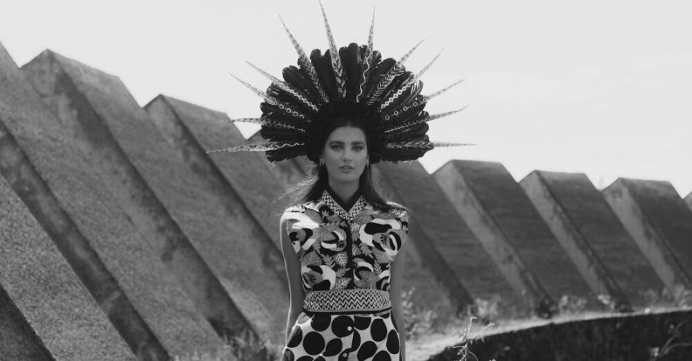 Editorials - A woman in a dress and headdress standing on a wall