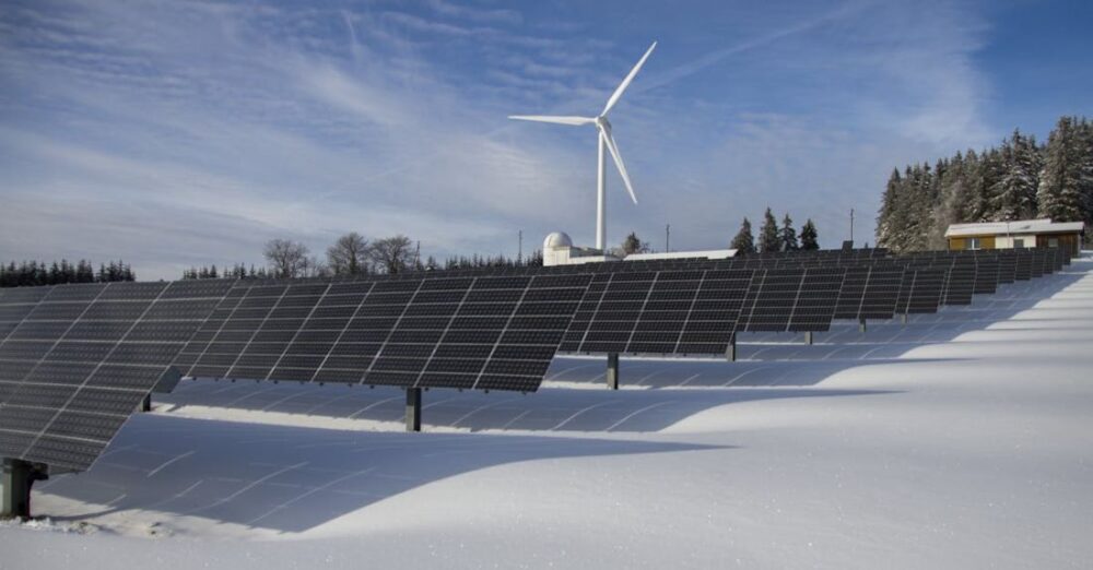 Renewable Energy - Solar Panels on Snow With Windmill Under Clear Day Sky