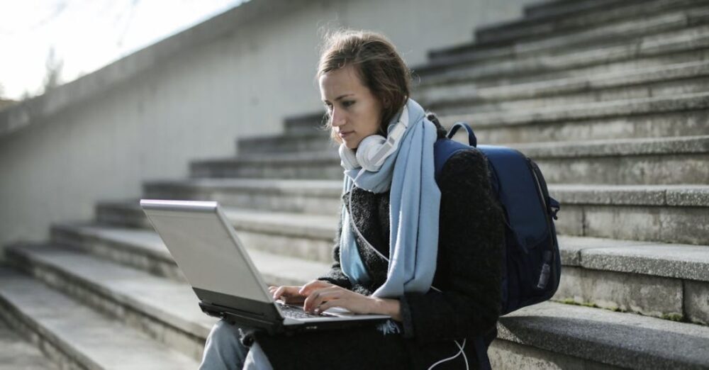 Distance Learning - Woman Sitting On Concrete Stairs Using Laptop