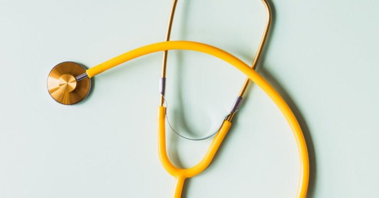 Preventive Medicine - Top view of yellow medical stethoscope placed on white surface during coronavirus pandemic